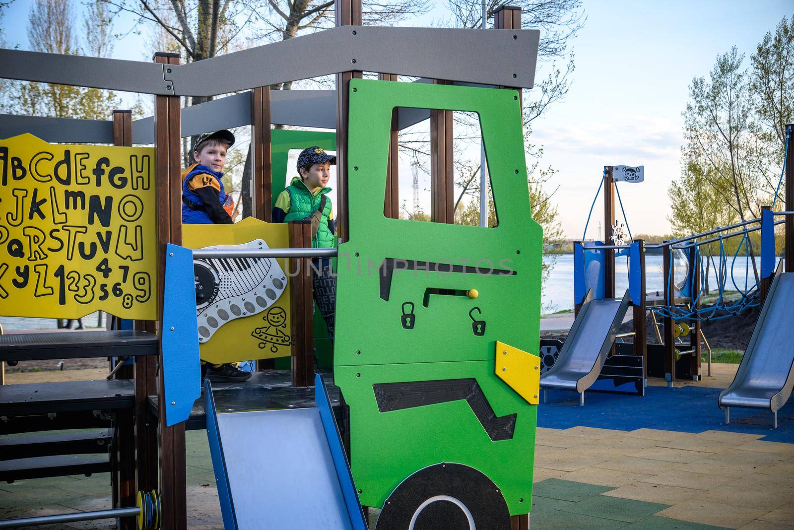 Portrait of cute boys playing on slide at playground on sunny morning.