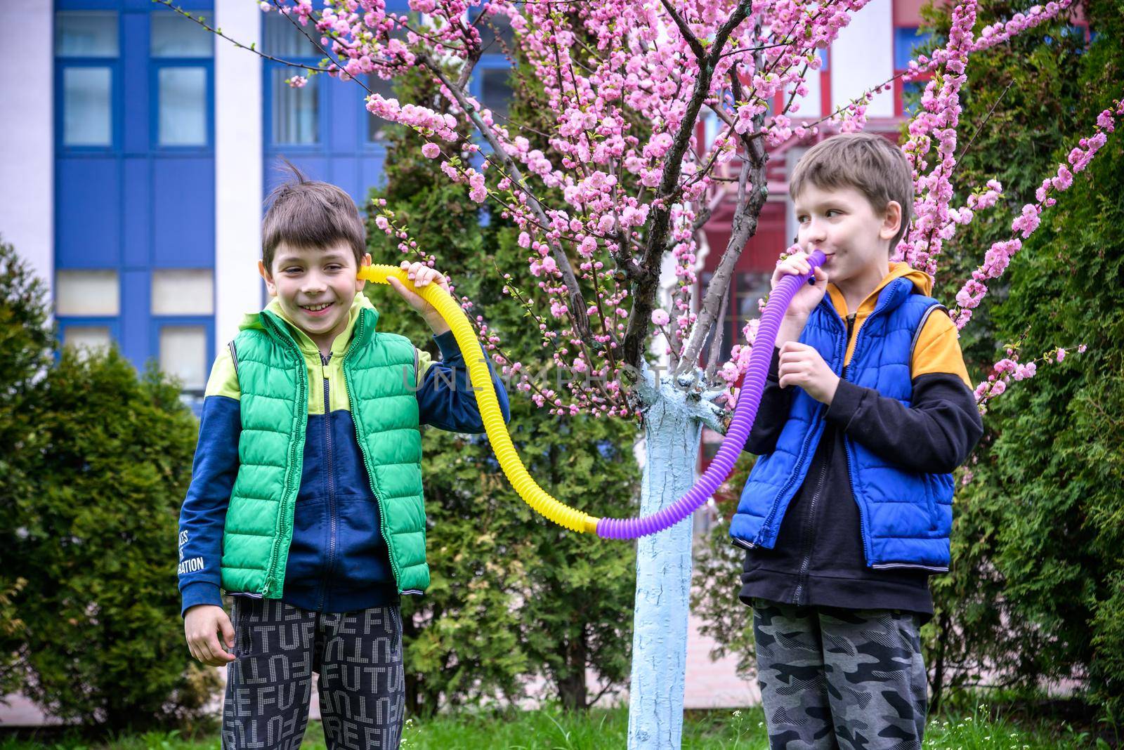 Colorful anti-stress fidget push pop tube toys for children. Flexible corrugated pipe in kids hands. Two Boys playing with sensory toys. Fun playing for developing imagination and fine motor skills.