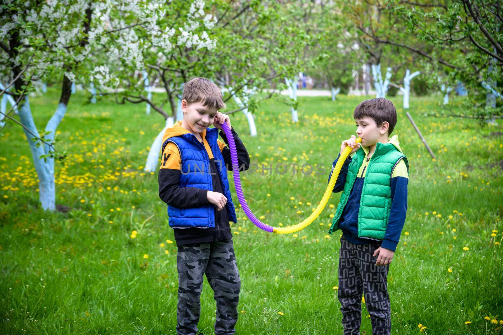 Colorful anti-stress fidget push pop tube toys for children. Flexible corrugated pipe in kids hands. Two Boys playing with sensory toys. Fun playing for developing imagination and fine motor skills.
