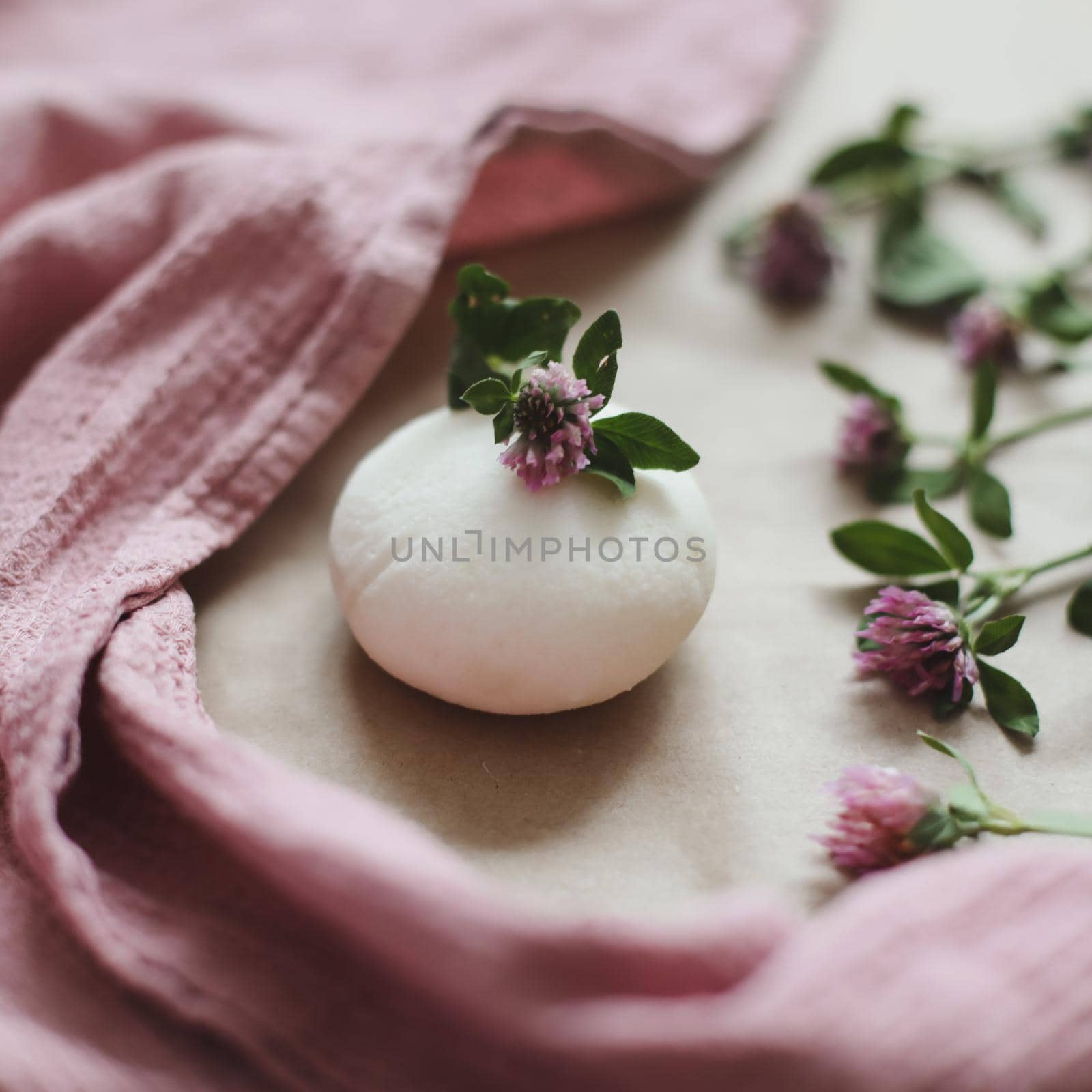 Handmade natural organic soap with flowers and pink towel on craft paper background top view with copyspace