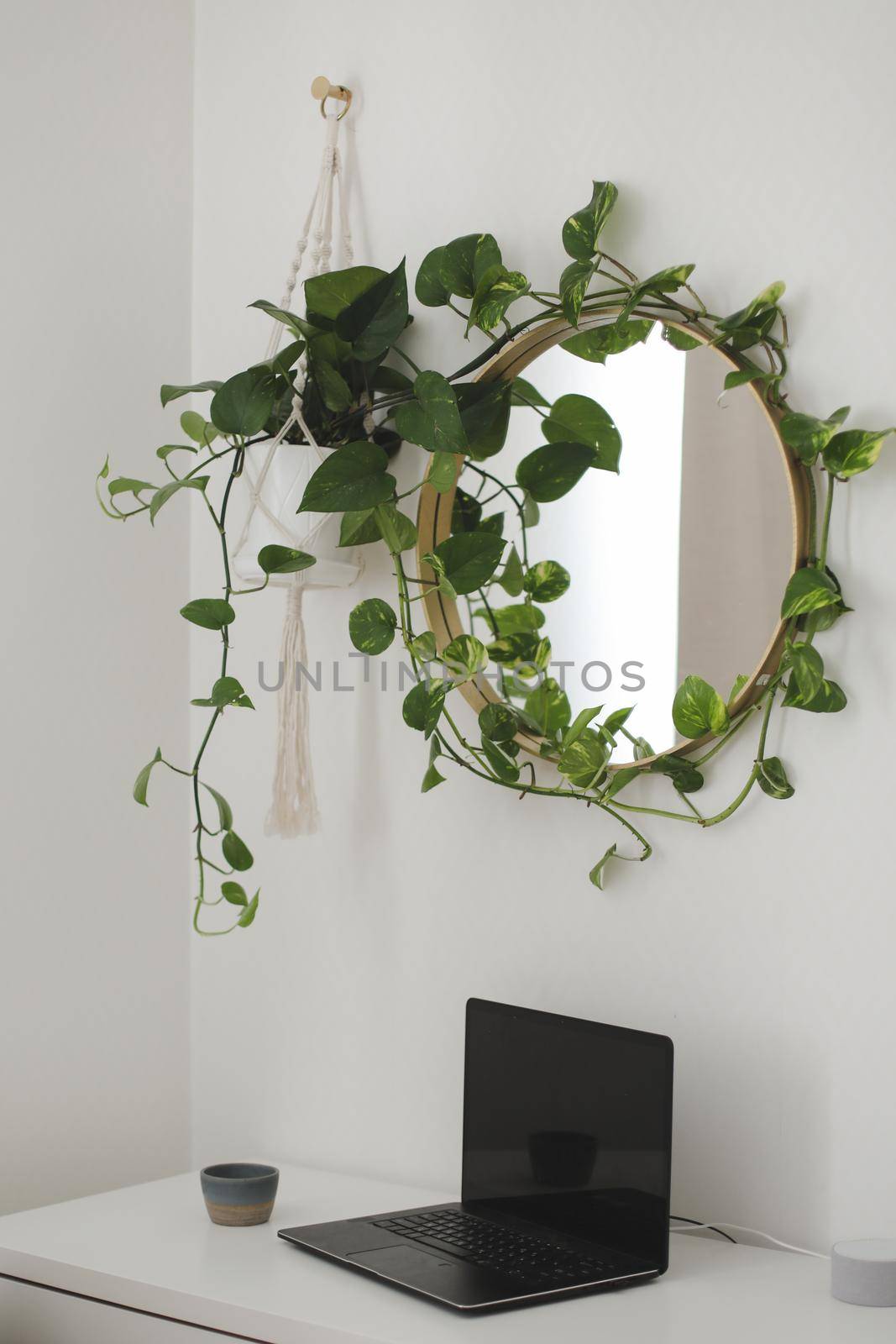 cozy workplace with a laptop on the table and a flower by the round mirror. home interior decoration