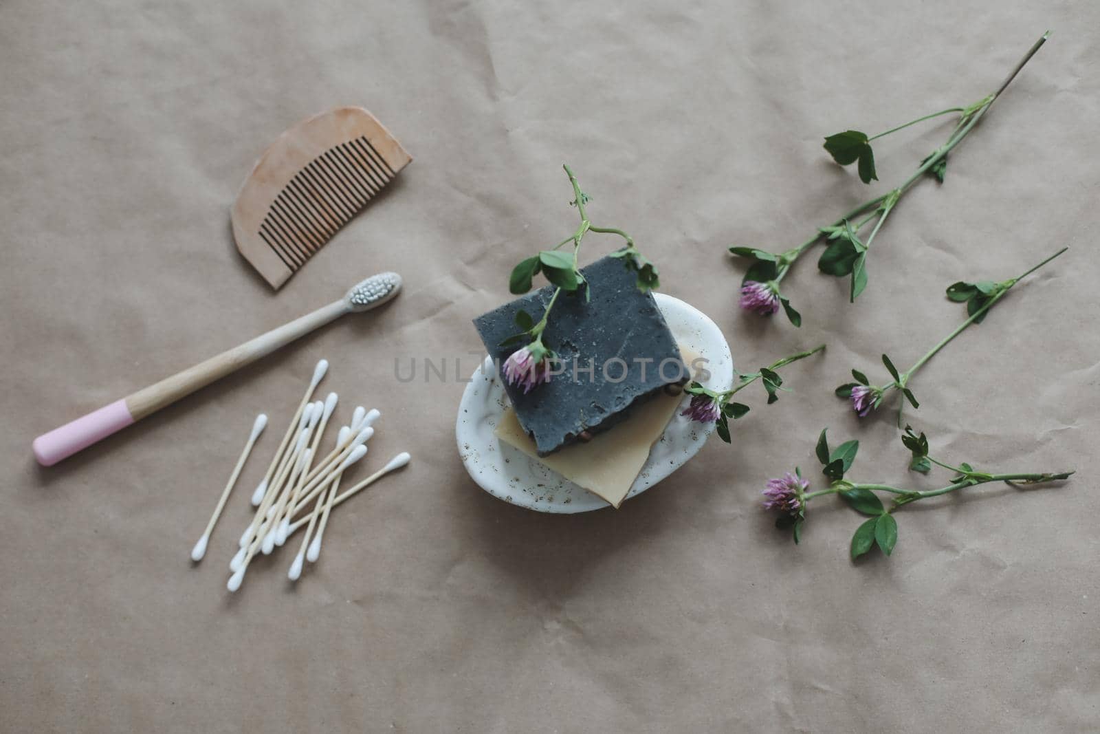 Soap bar or solid shampoo on a soap dish, bamboo toothbrush and towel top view with copyspace. Accessories for personal hygiene. Plastic free and eco friendly products in household.