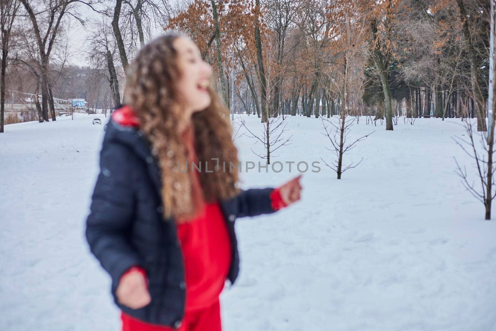 a young happy woman is having fun in a winter park, throwing snow, it is cold in her hands, the emissions are off scale. by mosfet_ua