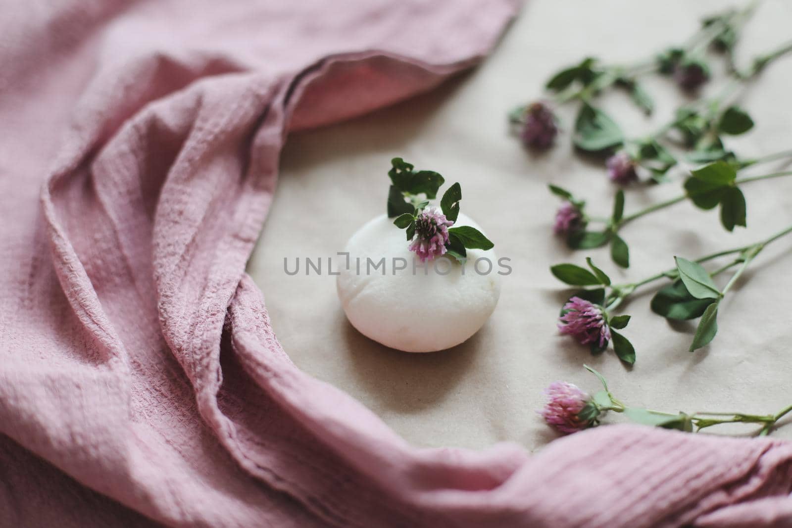 Handmade natural organic soap with flowers and pink towel on craft paper background top view with copyspace