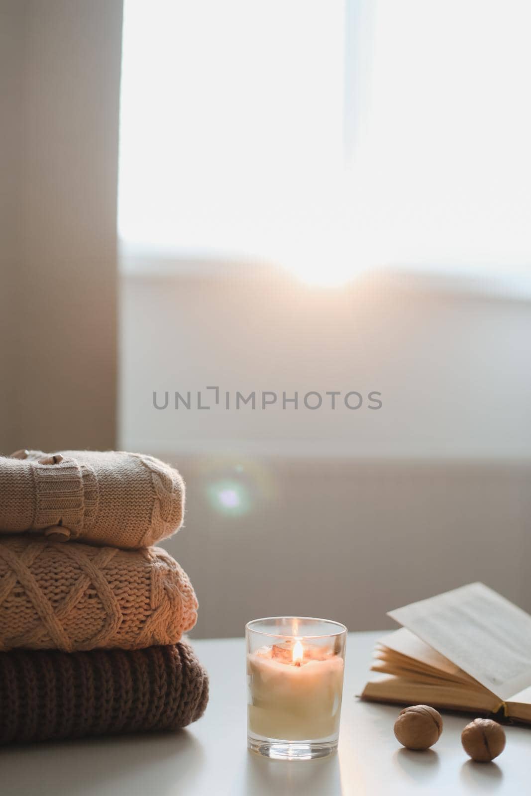 cozy comfortable hygge home atmosphere and still life with a cup, candle, book and sweaters by paralisart