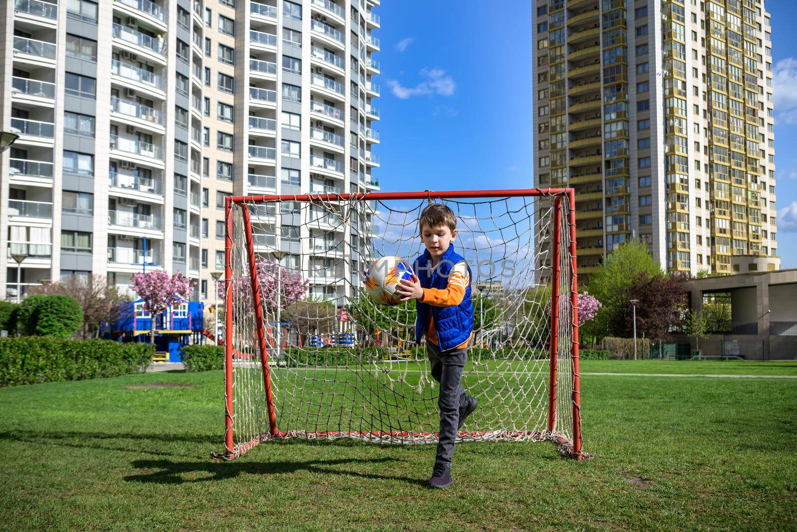 Little preschool boys friends playing soccer football on playground grass field outside. Happy authentic candid childhood lifestyle. Seasonal summer outdoor activity with ball for kids.