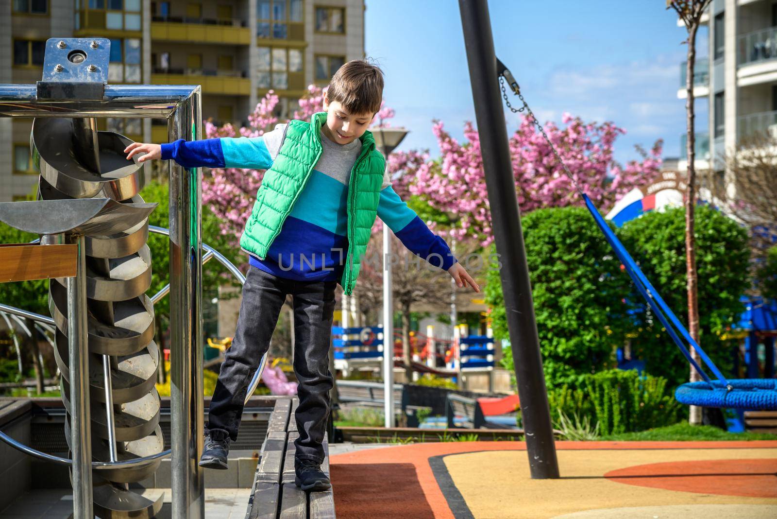 Children's obstacle course on a modern playground. Kid crossing a wooden bridge or other barriers using his body balance. Development of the child's agility and courage.