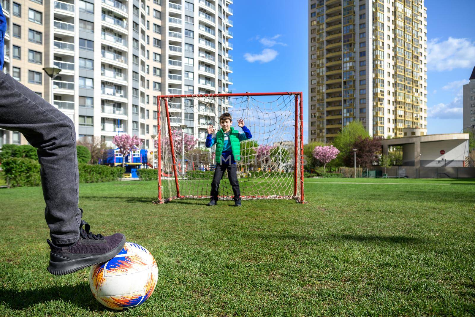 Little preschool boys friends playing soccer football on playground grass field outside. Happy authentic candid childhood lifestyle. Seasonal summer outdoor activity with ball for kids.