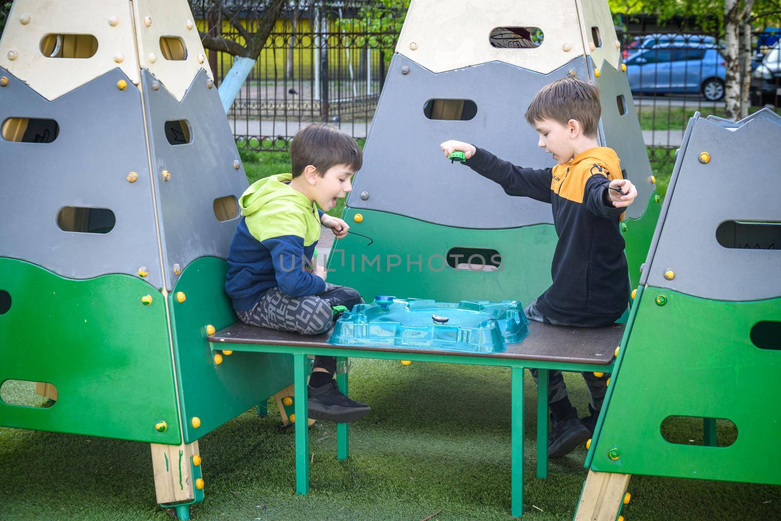 Two Boys playing with modern spin top outdoors. Entertainment game for children. Top, triggered by a trigger. Kids having a tournament on arena or battle field.