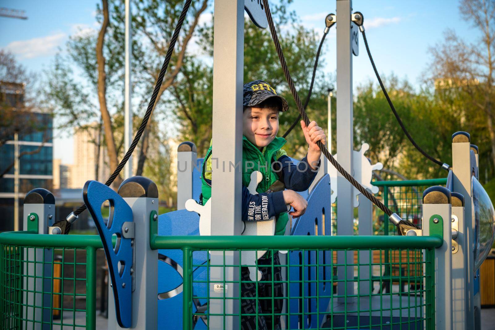 Boy as a captain or sailors play on the ship outdoors on sunny day. Kid has a lot of fun. Ship has colorful flags on wind by Kobysh