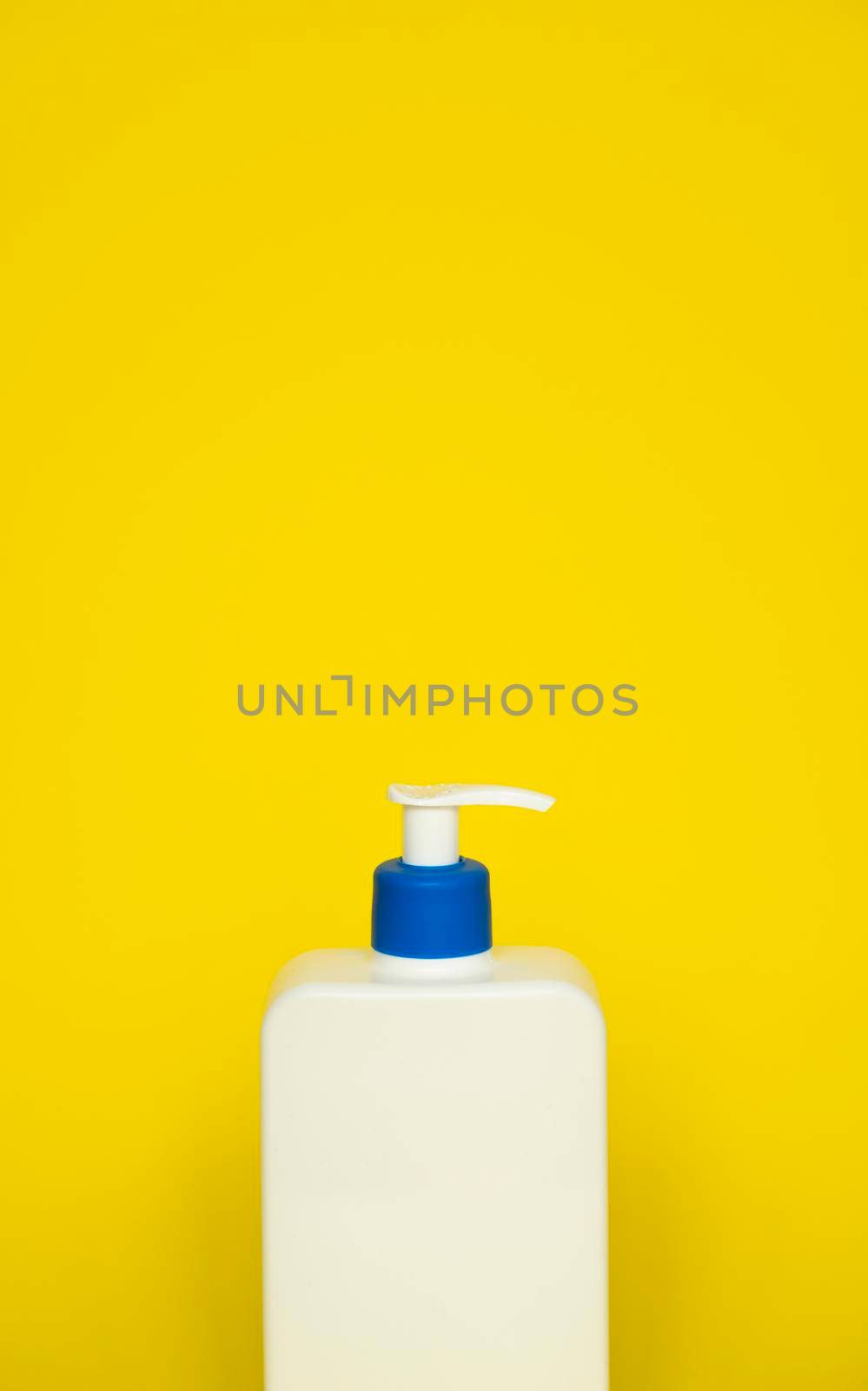 Liquid container for gel, lotion, cream, shampoo, bath foam. Cosmetic plastic bottle with dispenser pump on yellow background. Cosmetic packaging mockup with copy space