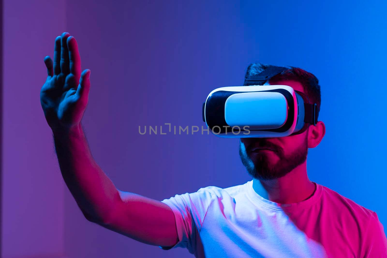 Portraite of young man gamer using virtual reality headset and playing favourite video games with a friends in metaverse. VR, future, gadgets, technology, education online, studying. by vovsht