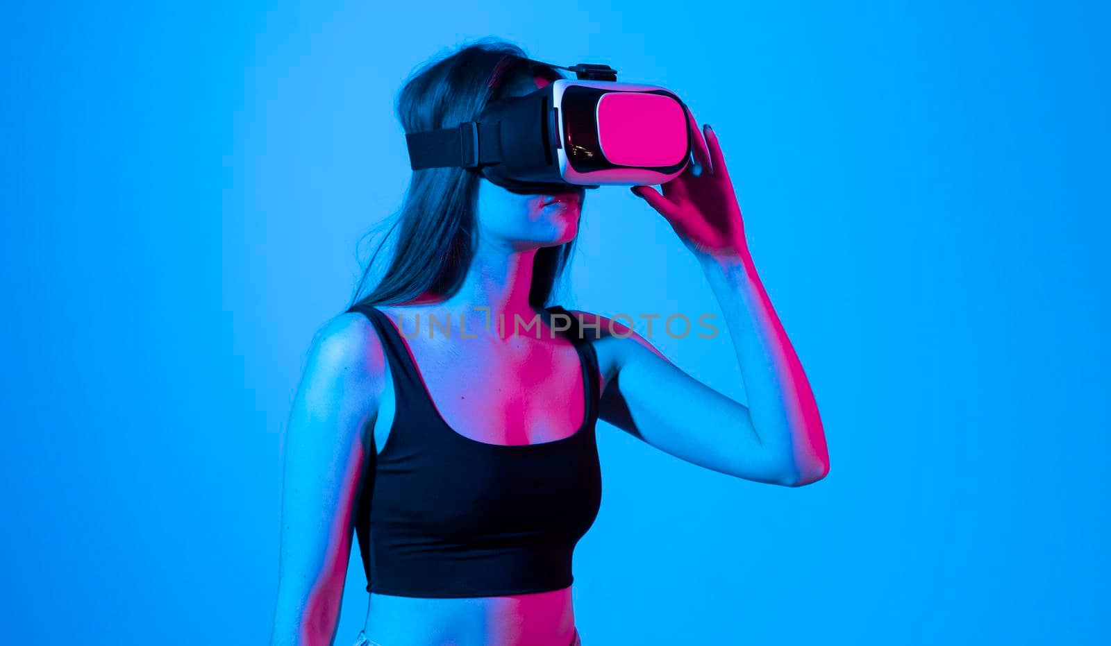 Young woman in a black t-shirt using the VR goggles and communicating with friends in a metaverse social network. Future technology concept. by vovsht