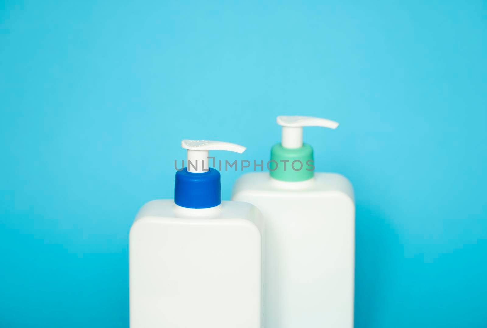 Liquid container for gel, lotion, cream, shampoo, bath foam. Cosmetic plastic bottle with dispenser pump on blue background. Cosmetic packaging mockup with copy space. by vovsht