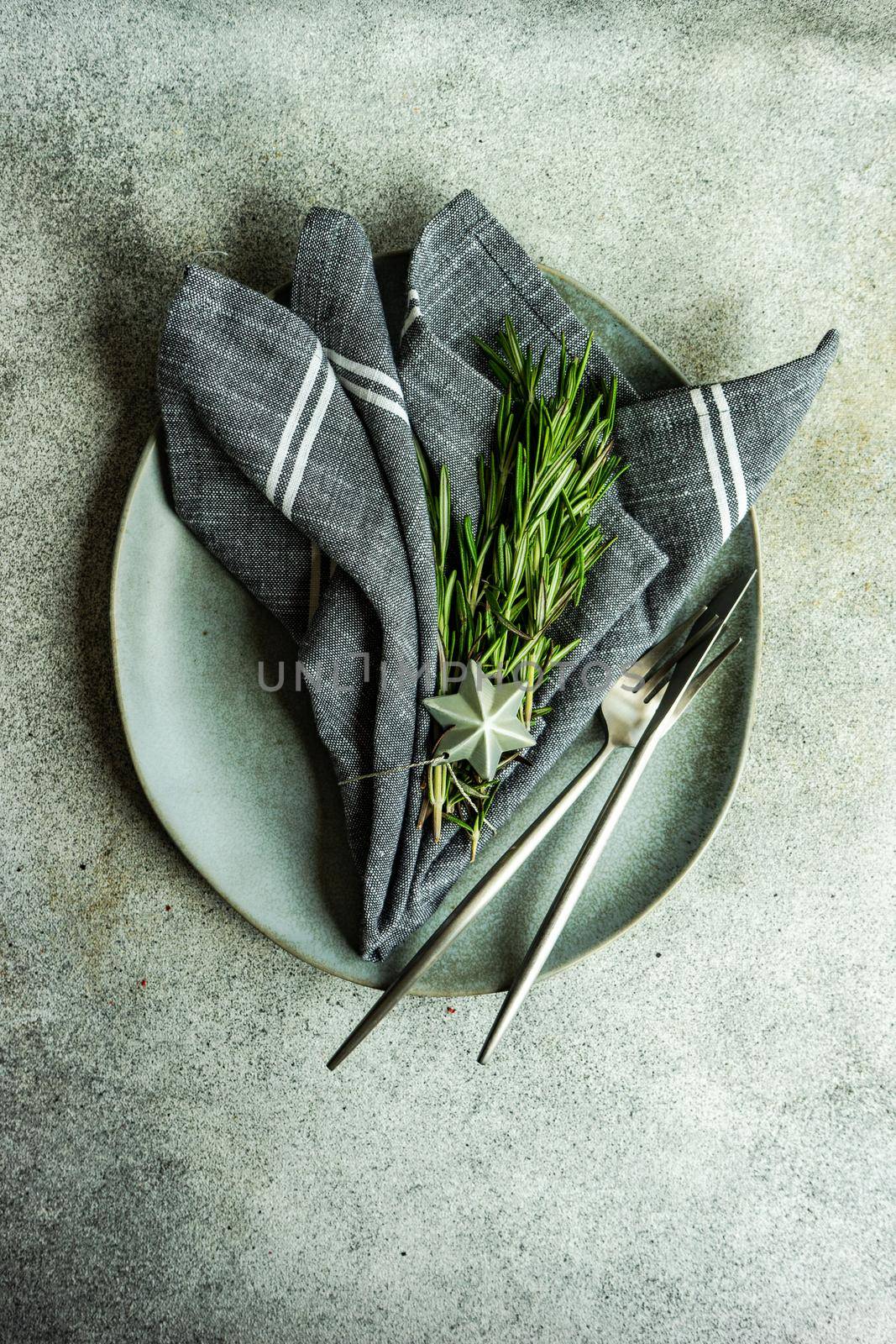 Minimalistic place setting with fresh rosemary herb on concrete table