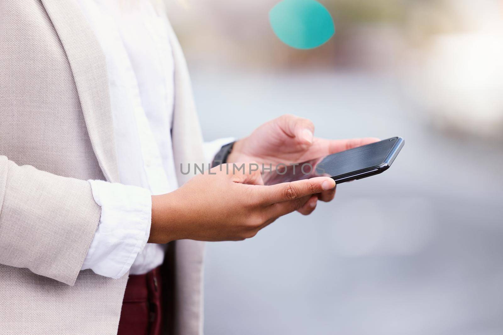 Communication is the key to success. an unrecognizable young businesswoman texting while walking through the city. by YuriArcurs