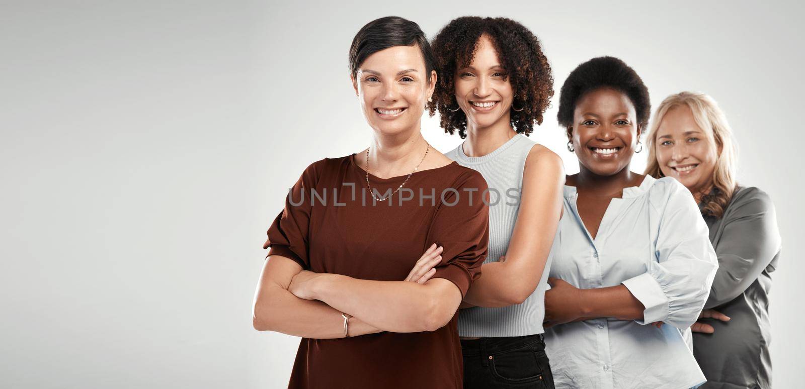 The line of strong women doesnt end with me. a diverse group of women standing together in the studio with their arms folded. by YuriArcurs