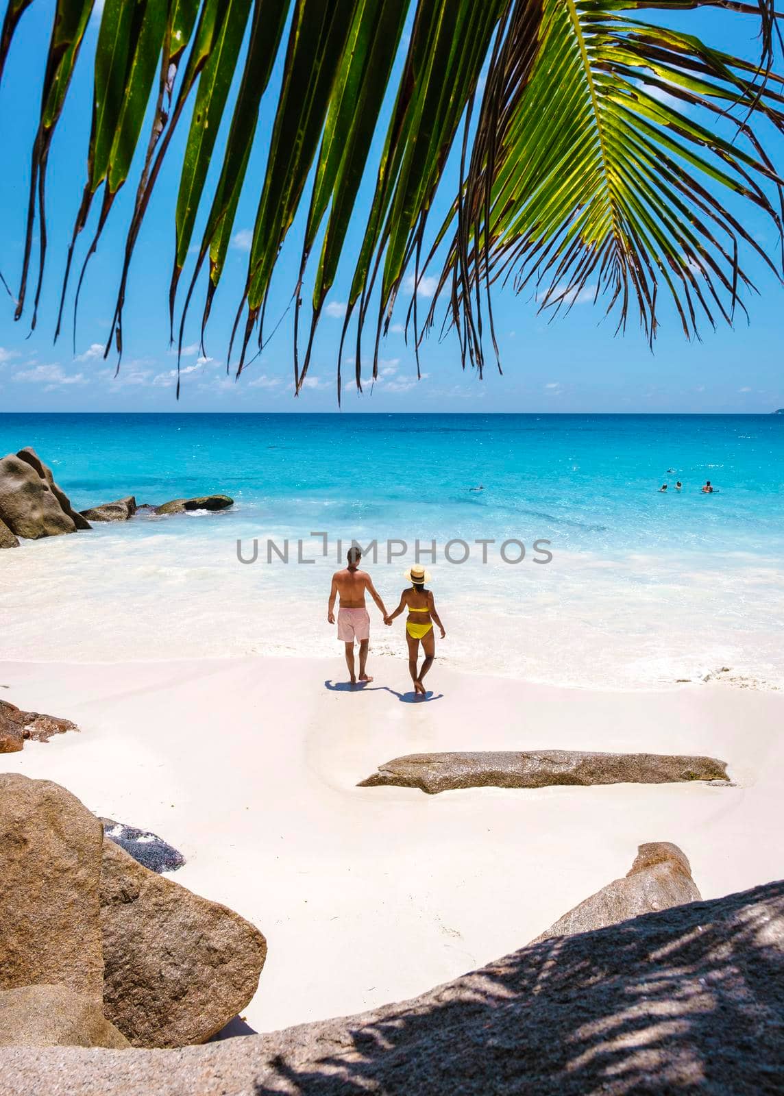 Anse Georgette Praslin Seychelles, young couple men and woman on a tropical beach by fokkebok