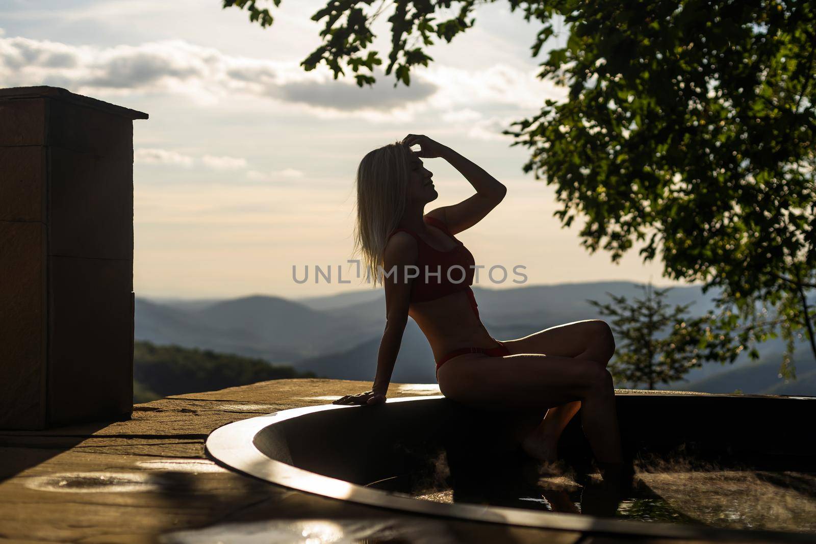 Woman relaxing in hot bath outdoors, enjoying thermal spa at mountains. summer holidays in the mountains, hot water treatments concept