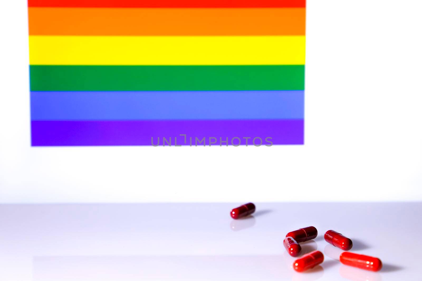 Six Red capsules and rainbow flag in the background