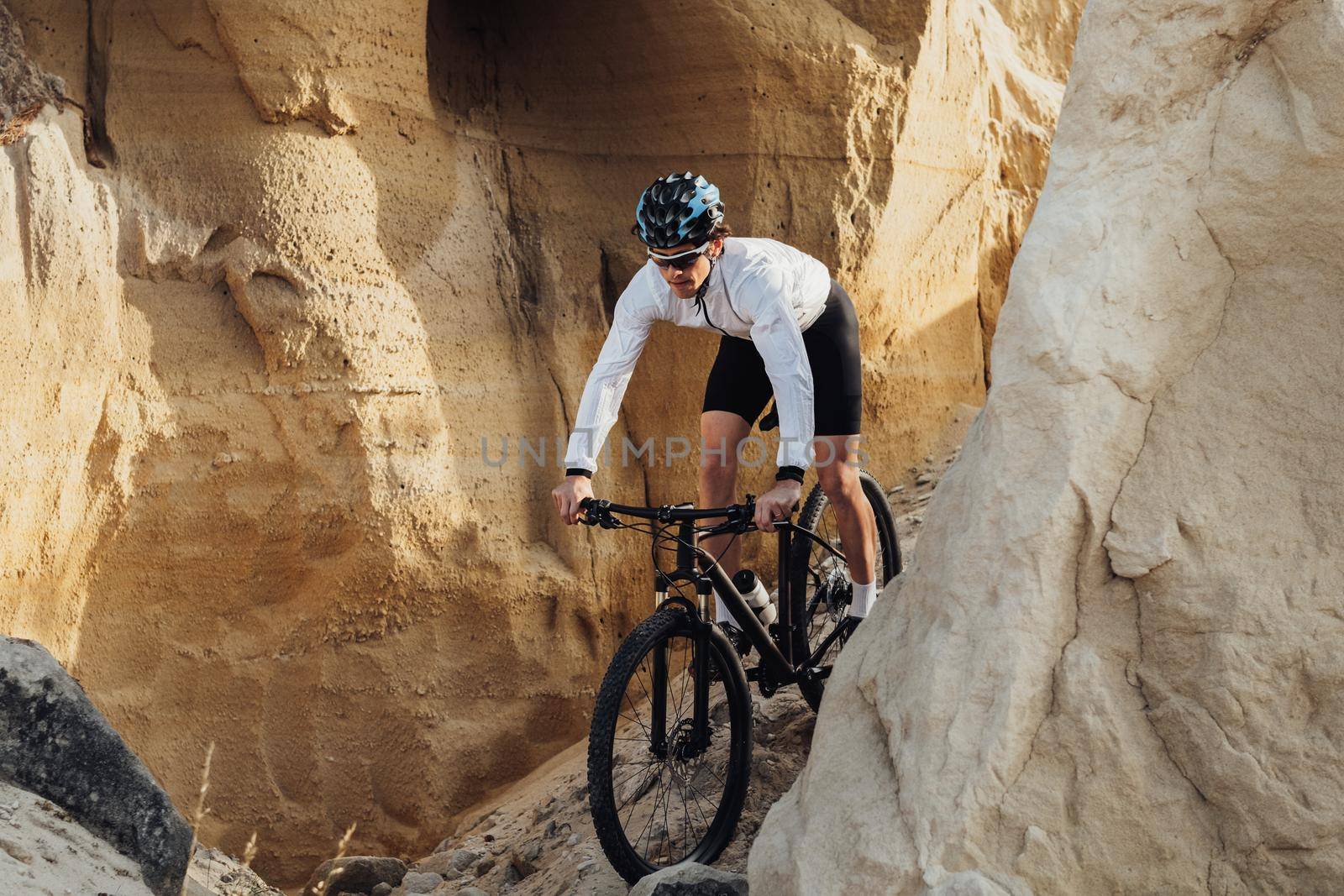 Adult Man Riding Bike Outdoors, Professional Equipped Cyclist on Trail with Giant Sandy Stones
