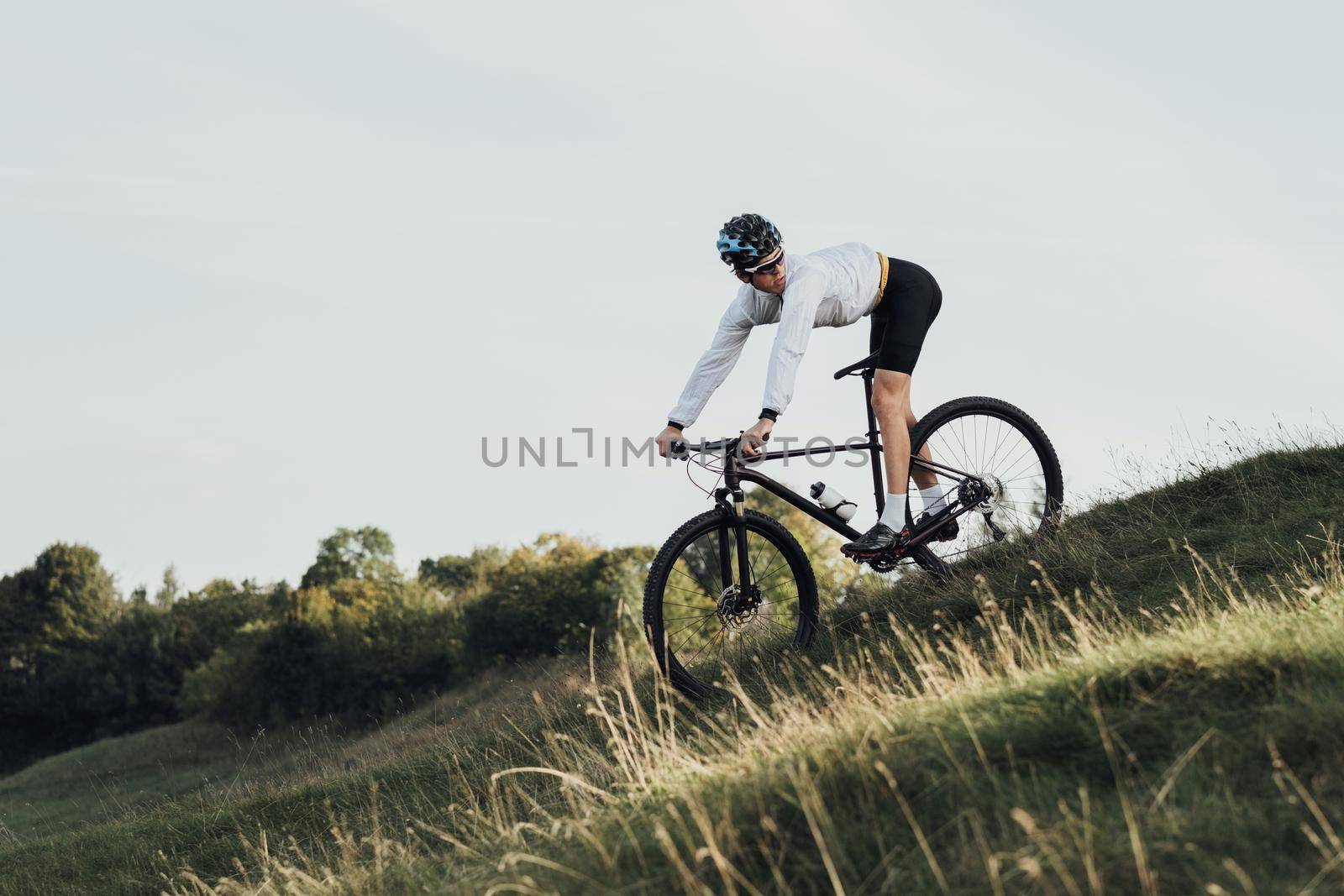 Professional Cyclist Descends a Slope on Mountain Bike, Sportsman Going Down from Hill on Bicycle, Copy Space