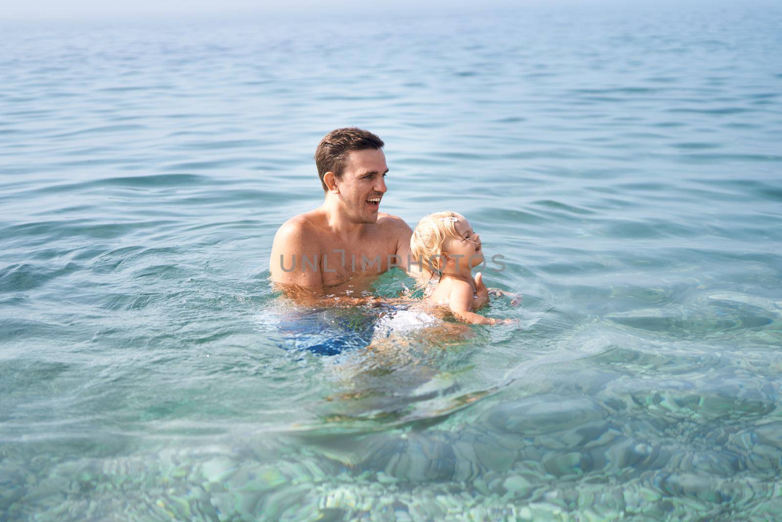 Dad teaches little girl to swim in the sea. High quality photo
