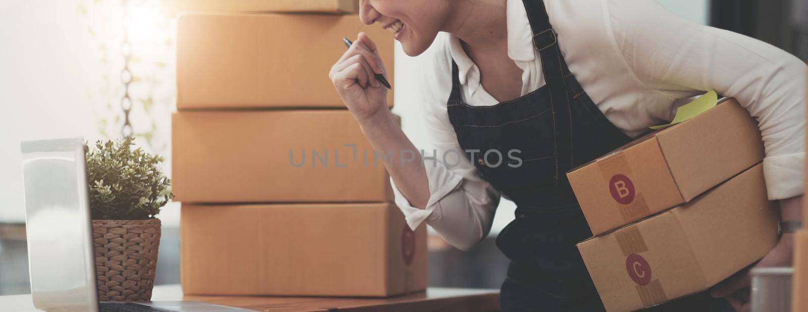 Portrait of Starting small businesses SME owners female entrepreneurs working on receipt box and check online orders to prepare to pack the boxes, sell to customers, SME business ideas online. by wichayada