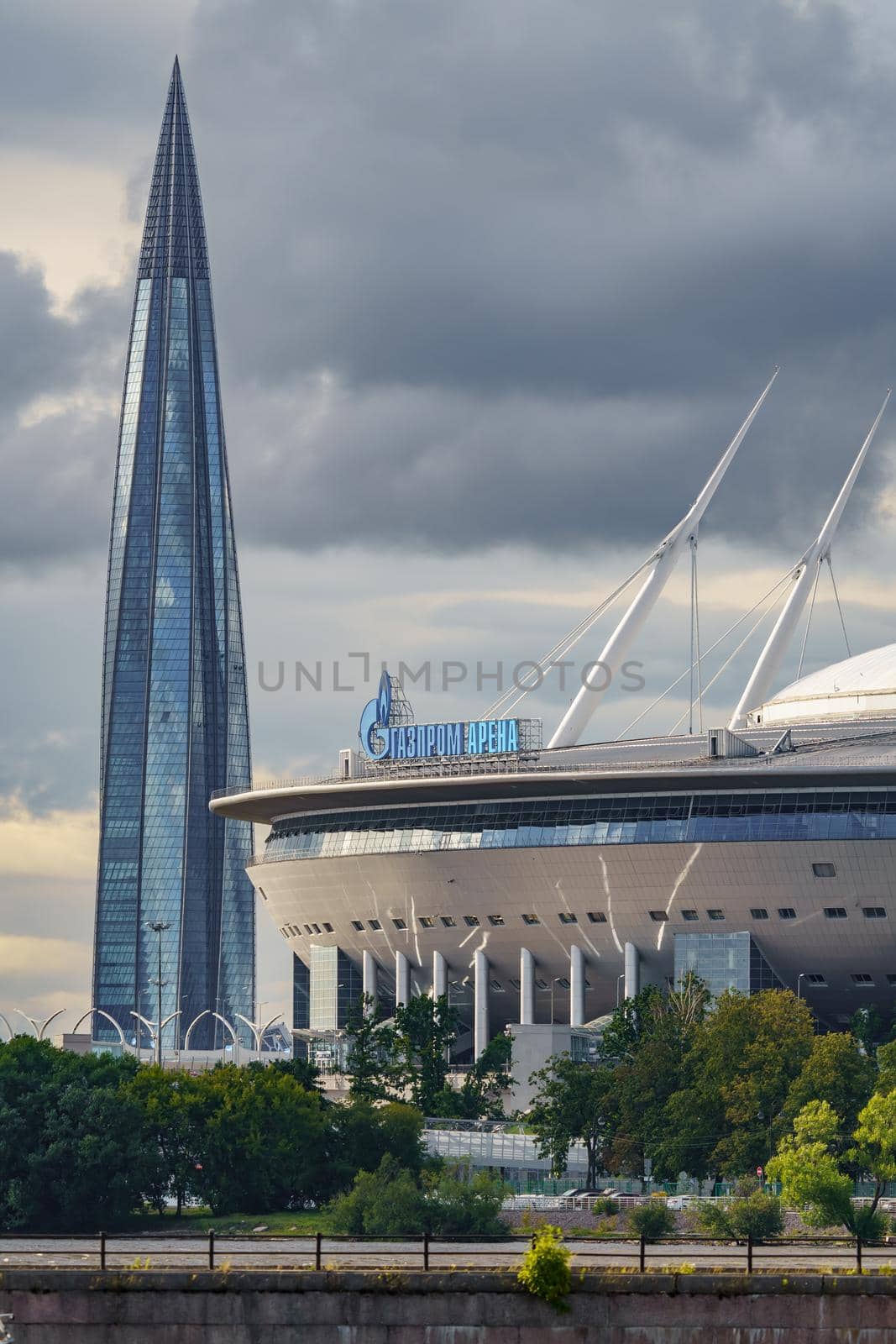 Russia, St. Petersburg, 29 July 2022: The new building of football stadium Gazprom Arena, the sliding metal roof glitters with spires in the sun, the skyscraper Lakhta for the gas company Gazprom. High quality photo