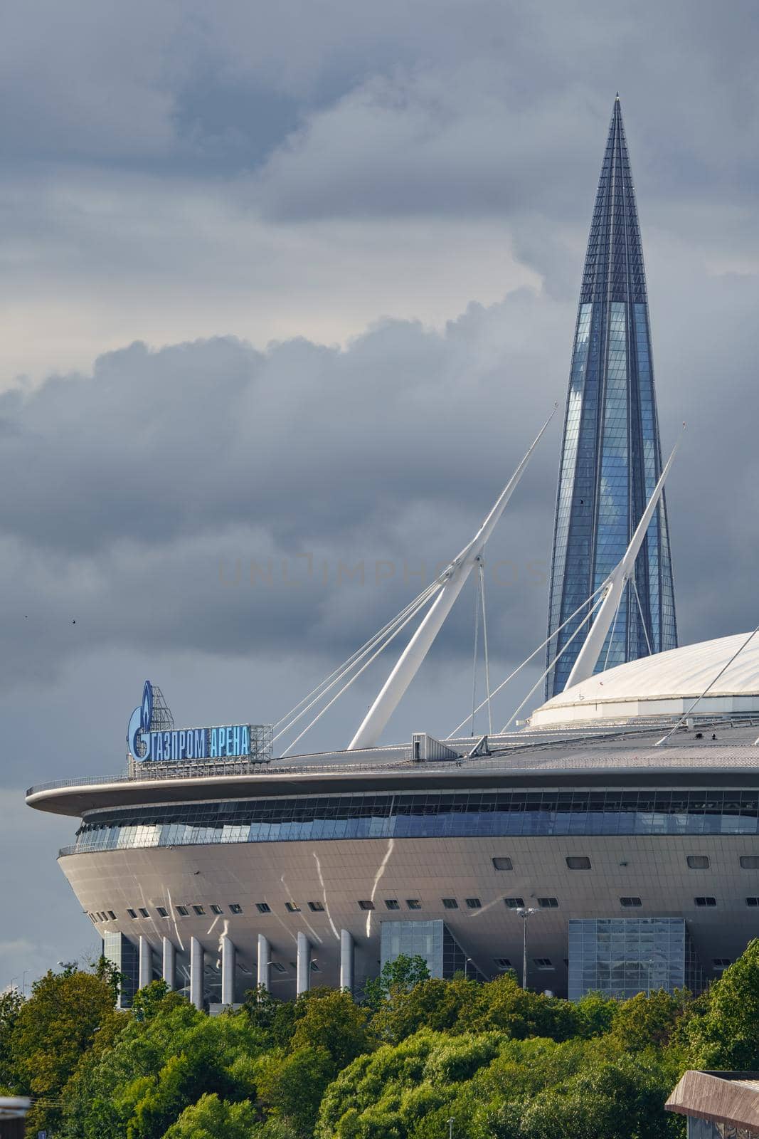 Russia, St. Petersburg, 29 July 2022: The new building of football stadium Gazprom Arena, the sliding metal roof glitters with spires in the sun, the skyscraper Lakhta for the gas company Gazprom. High quality photo