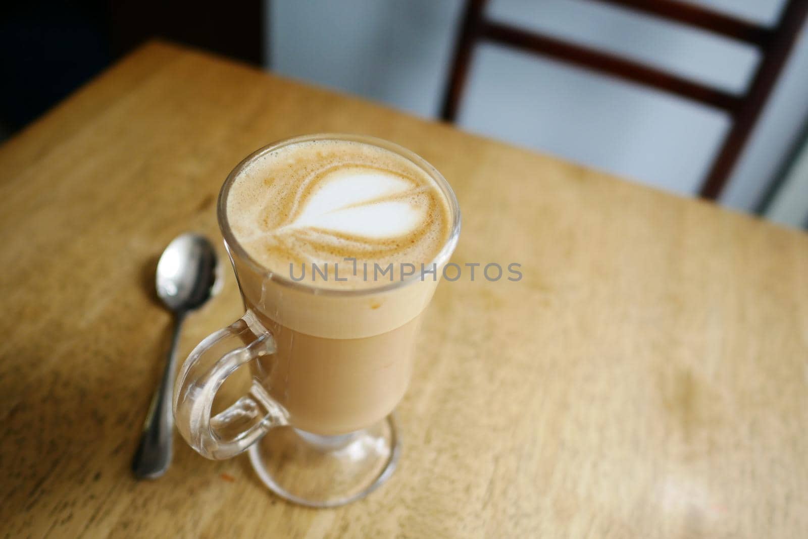 a cup of late coffee with flower shape design on top at cafe .