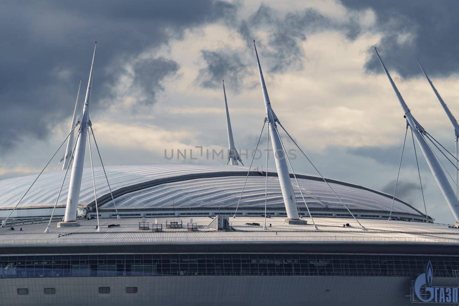 Russia, St. Petersburg, 29 July 2022: The new building of football stadium Gazprom Arena, the sliding metal roof glitters with spires in the sun, the gas company Gazprom. High quality photo