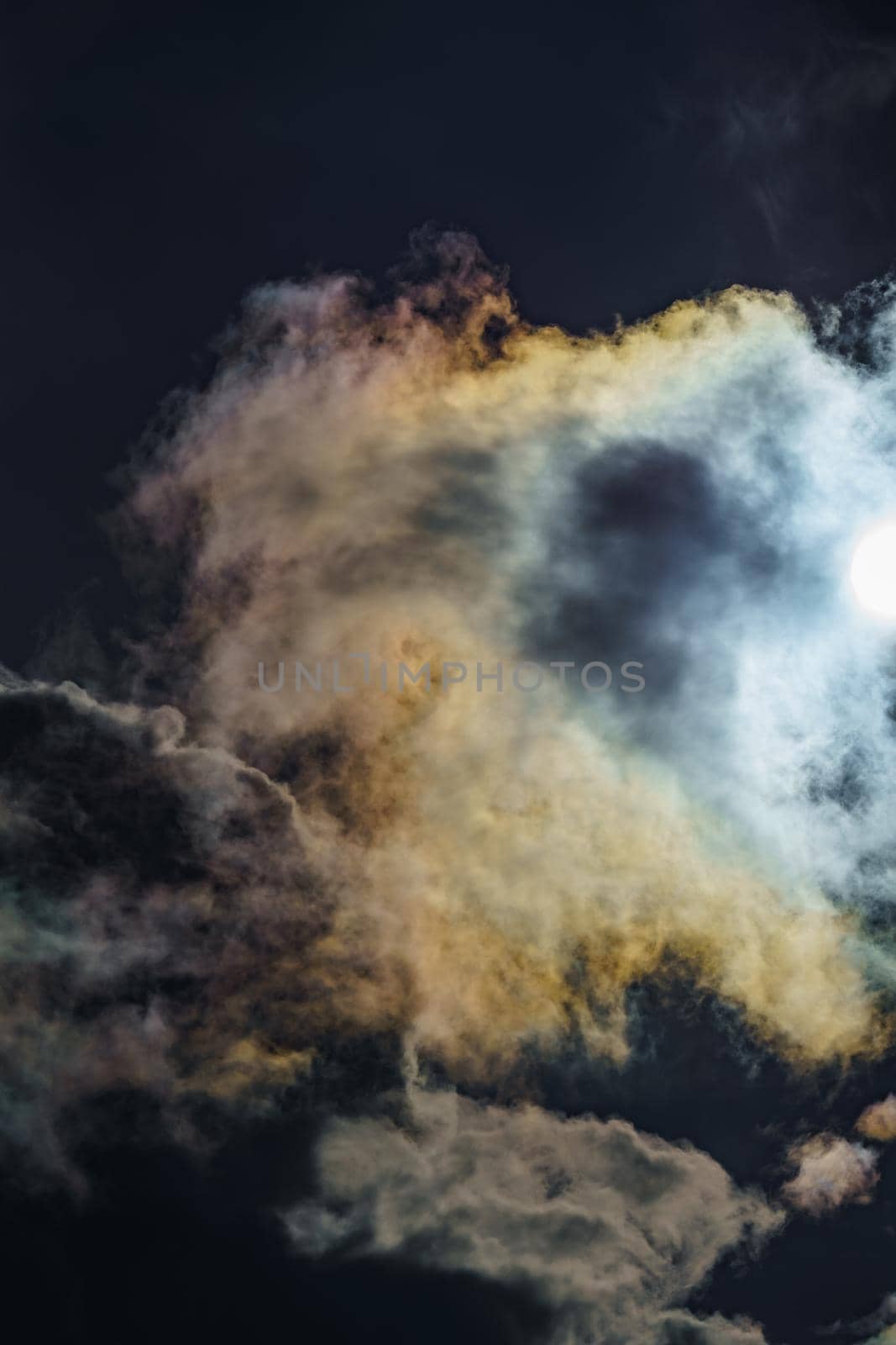 Diffraction of light on drops of supercooled water in clouds, rainbow clouds against the blue sky in clear sunny weather, irisation of cumulus clouds, optical phenomenon, spectral colors. High quality photo