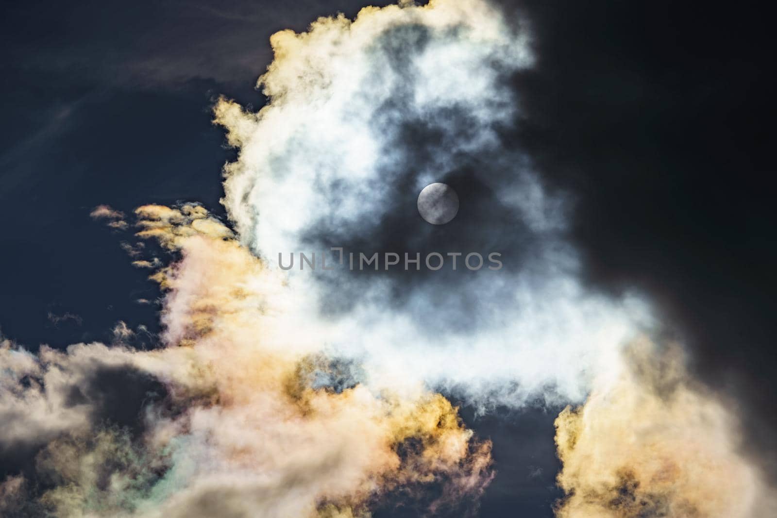 Diffraction of light on drops of supercooled water in clouds, rainbow clouds against the blue sky in clear sunny weather, irisation of cumulus clouds, optical phenomenon, spectral colors. High quality photo