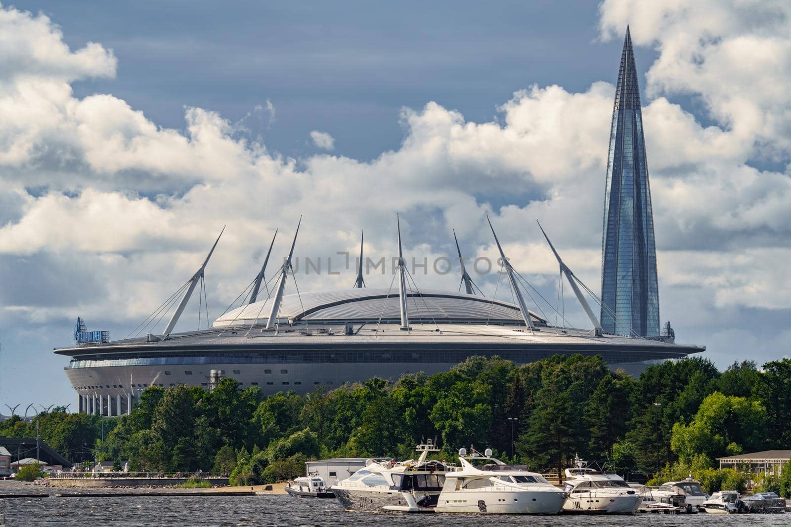 Russia, St. Petersburg, 29 July 2022: The new building of football stadium Gazprom Arena, sailing and motor boats are moored near embankment, the skyscraper Lakhta for the gas company Gazprom. High quality photo