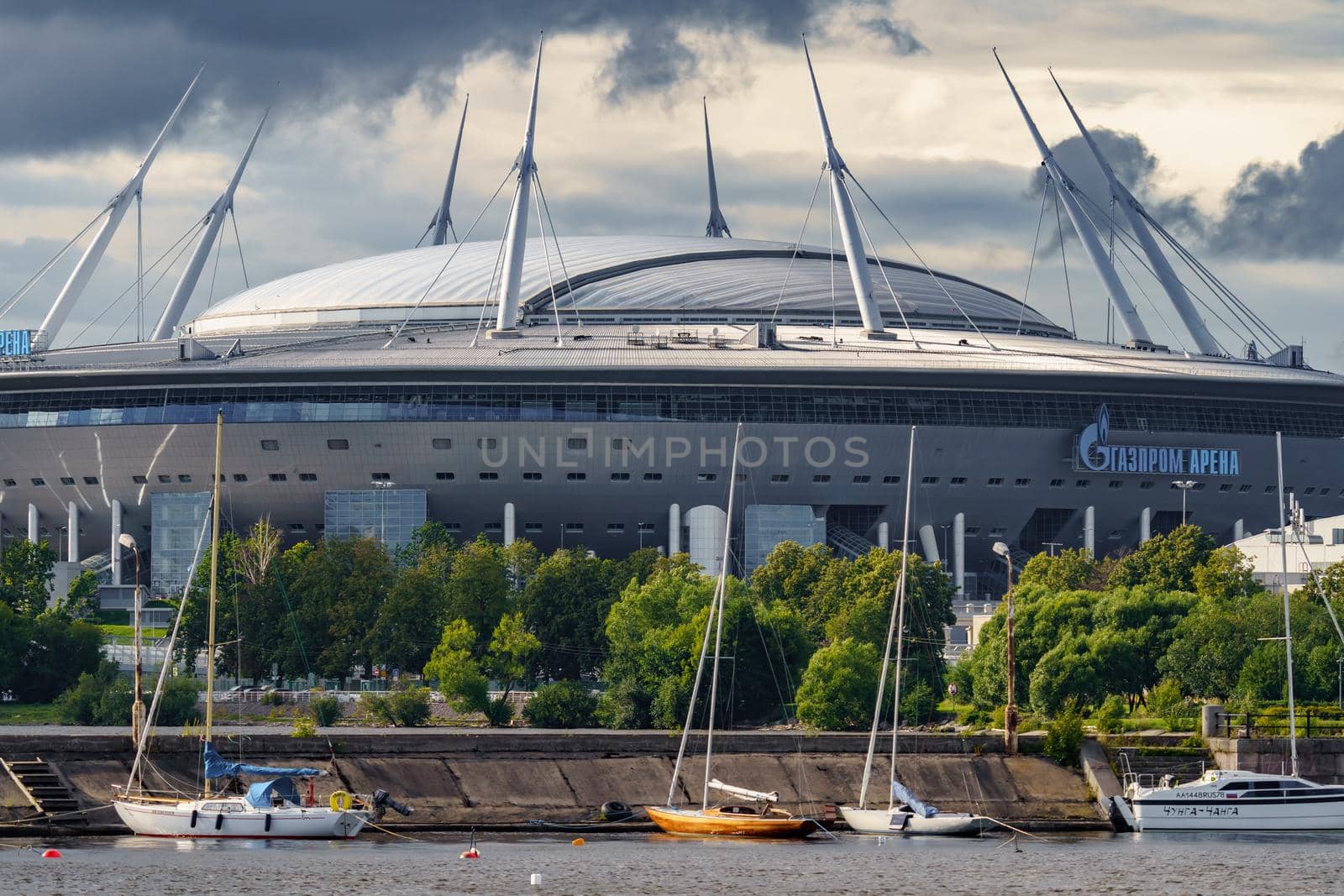 Russia, St. Petersburg, 29 July 2022: The new building of football stadium Gazprom Arena, sailing and motor boats are moored near embankment, the gas company Gazprom. High quality photo
