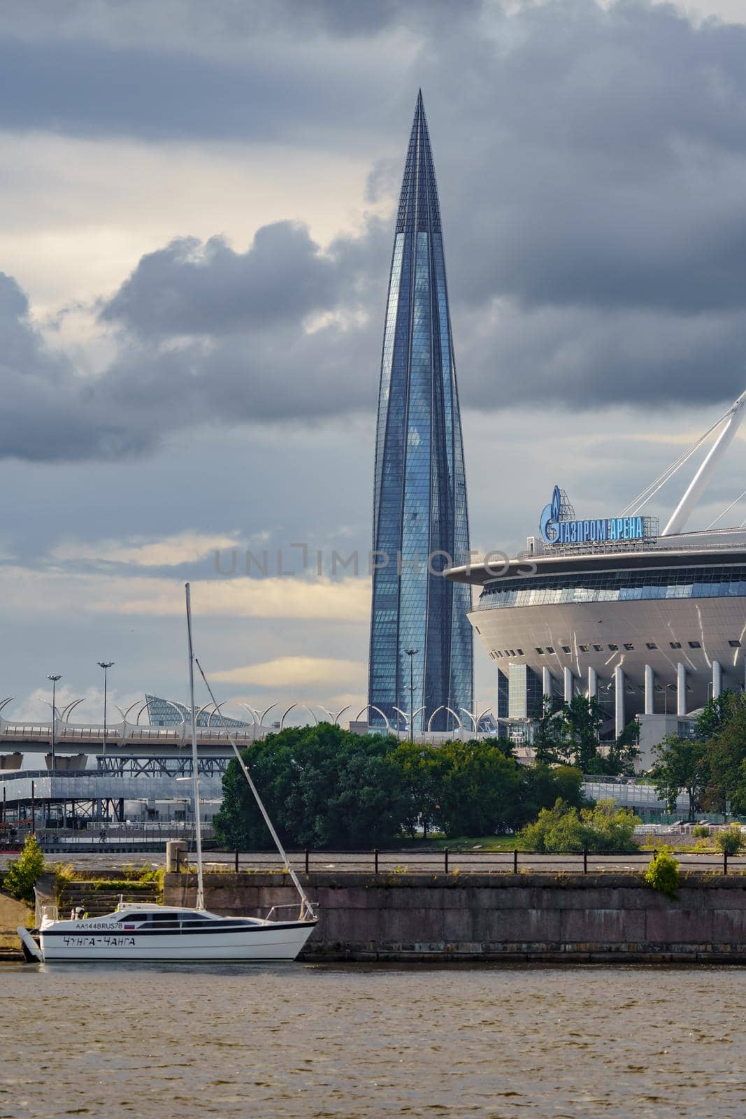 Russia, St. Petersburg, 29 July 2022: The new building of football stadium Gazprom Arena, the sliding metal roof glitters with spires in the sun, the skyscraper Lakhta for the gas company Gazprom. High quality photo