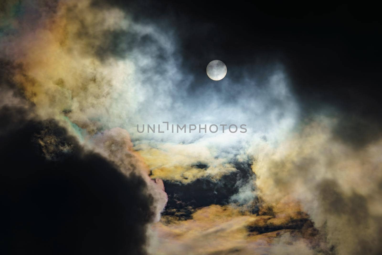 Diffraction of light on drops of supercooled water in clouds, rainbow clouds against the blue sky in clear sunny weather, irisation of cumulus clouds, optical phenomenon, spectral colors. High quality photo