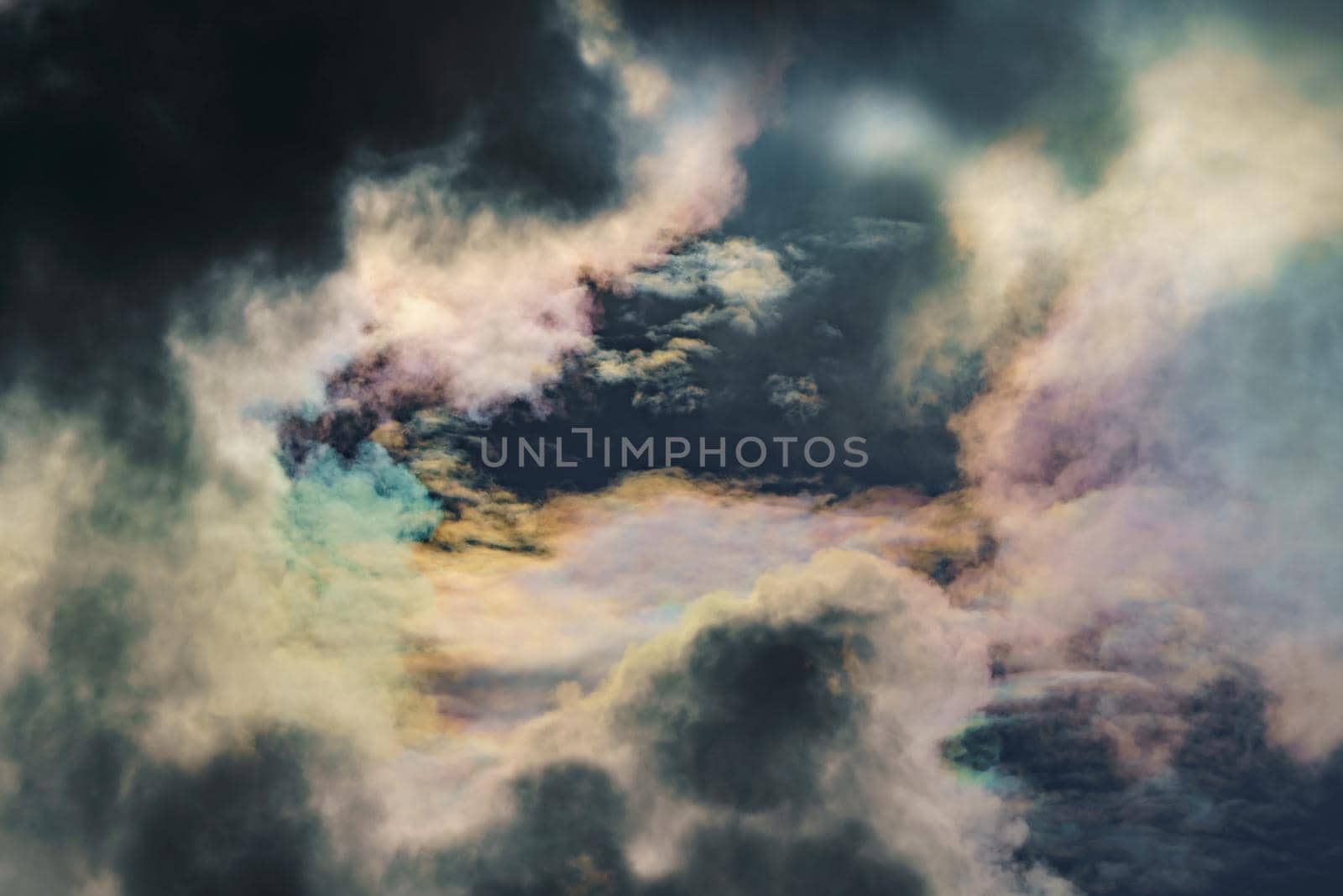 Diffraction of light on drops of supercooled water in clouds, rainbow clouds against the blue sky in clear sunny weather, irisation of cumulus clouds, optical phenomenon, spectral colors. High quality photo