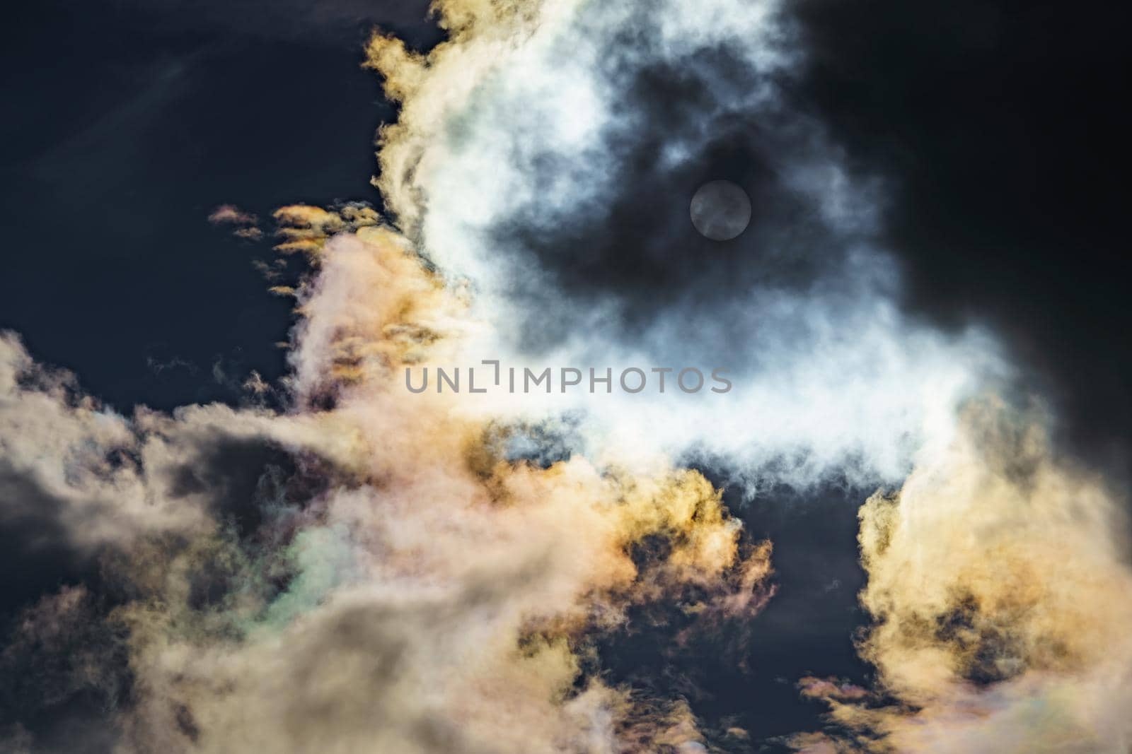 Diffraction of light on drops of supercooled water in clouds, rainbow clouds against the blue sky in clear sunny weather, irisation of cumulus clouds, optical phenomenon, spectral colors. High quality photo