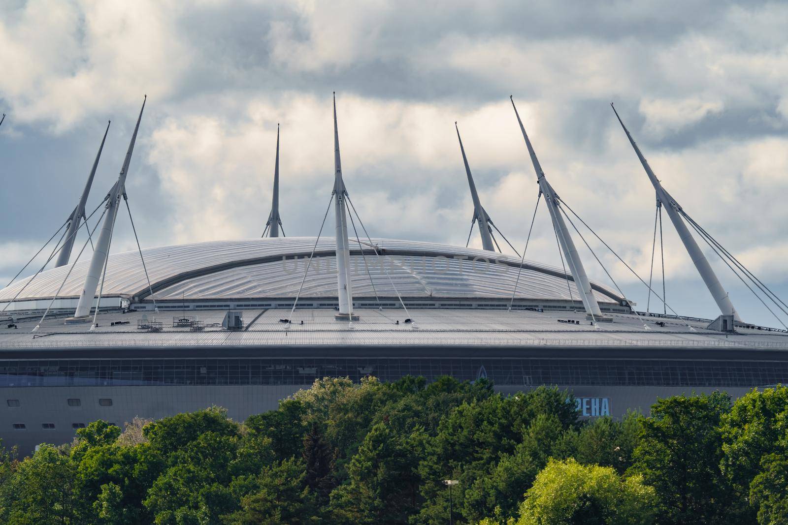 Russia, St. Petersburg, 29 July 2022: The new building of football stadium Gazprom Arena, the sliding metal roof glitters with spires in the sun, the gas company Gazprom. High quality photo