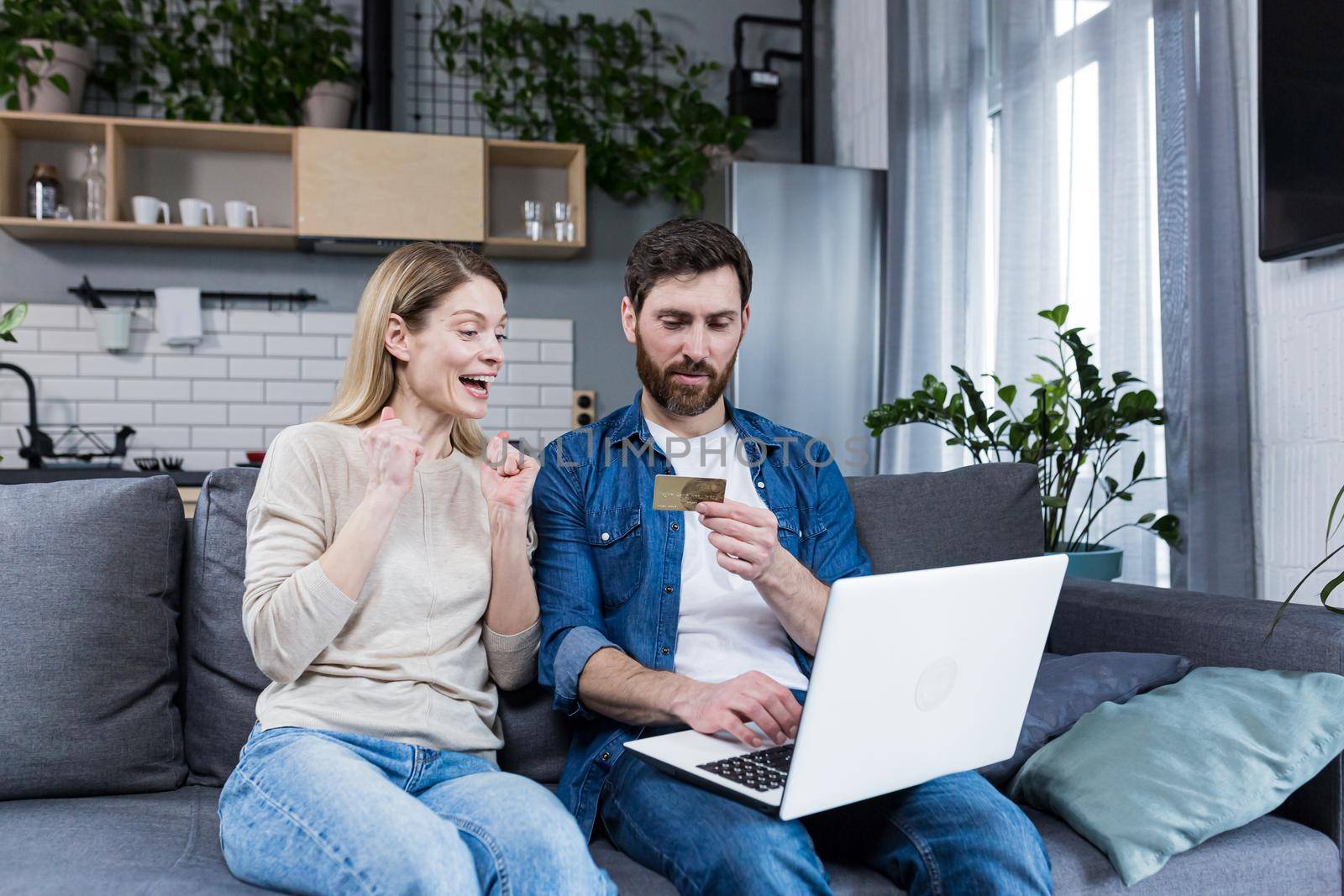 Online shopping. Man and woman shopping online from a notebook, holding a credit card by voronaman