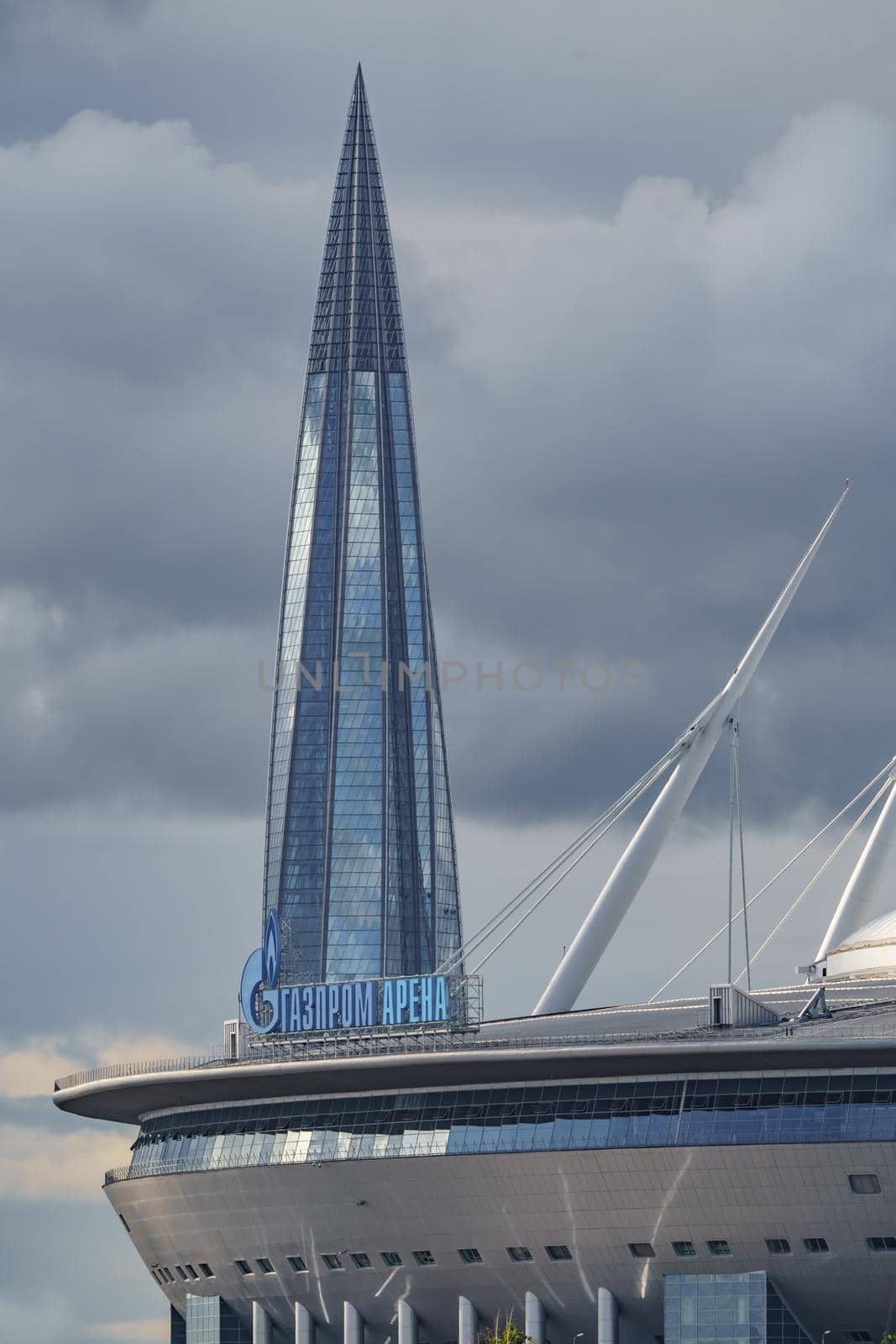 Russia, St. Petersburg, 29 July 2022: The new building of football stadium Gazprom Arena, the sliding metal roof glitters with spires in the sun, the skyscraper Lakhta for the gas company Gazprom. High quality photo