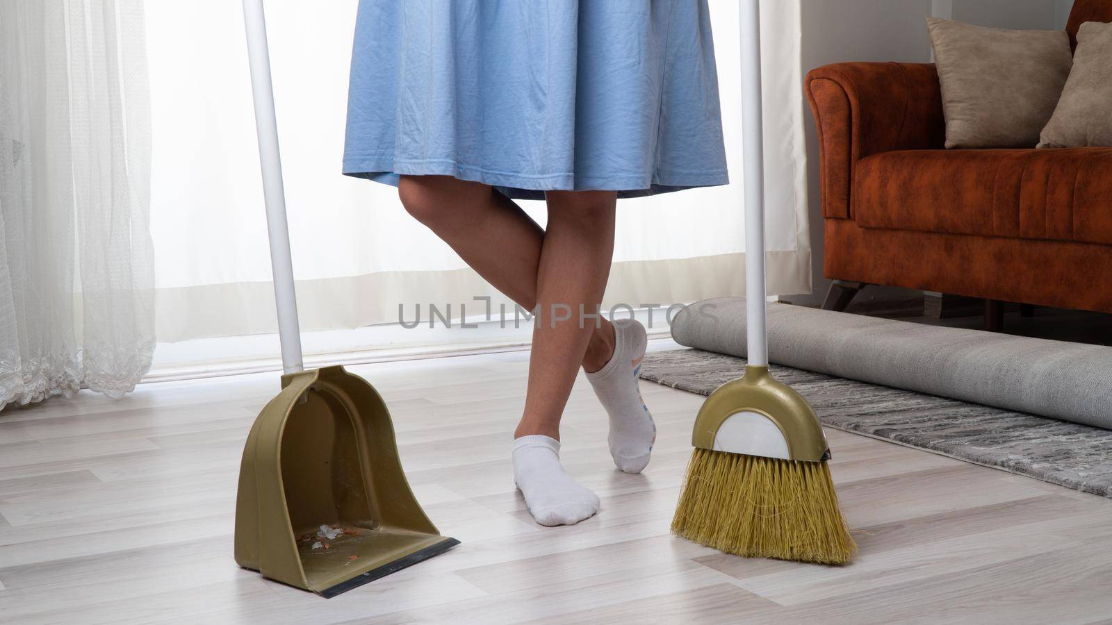 A woman stands between a broom brush and a scoop leg crossed by voktybre