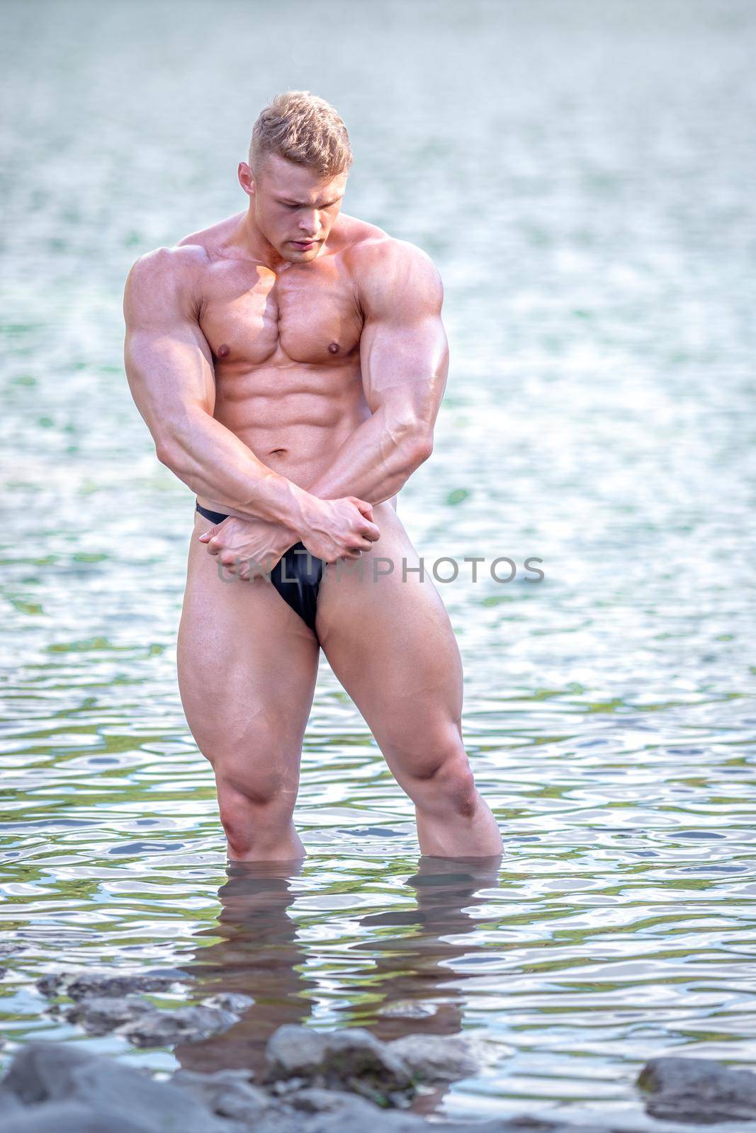 male bodybuilder by the water in nature.