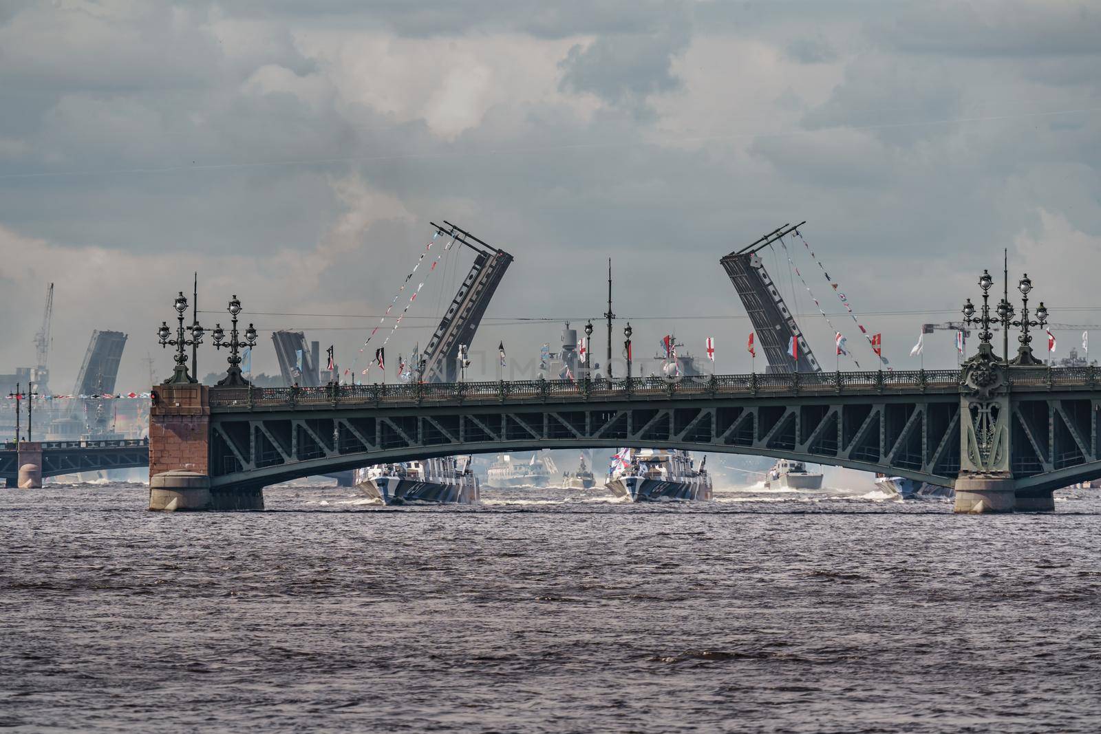 Russia, St. Petersburg, 28 July 2022: A lot of warships goes along the Neva River under open bridges at the time of the rehearsal of the celebration of the day of the Navy in sunny weather. High quality photo