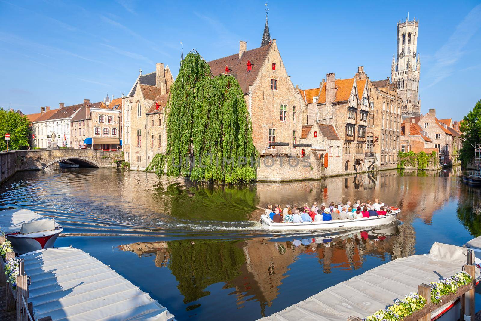Boat cruise crossing Rozenhoedkaai canal with reflection, Bruges, Belgium