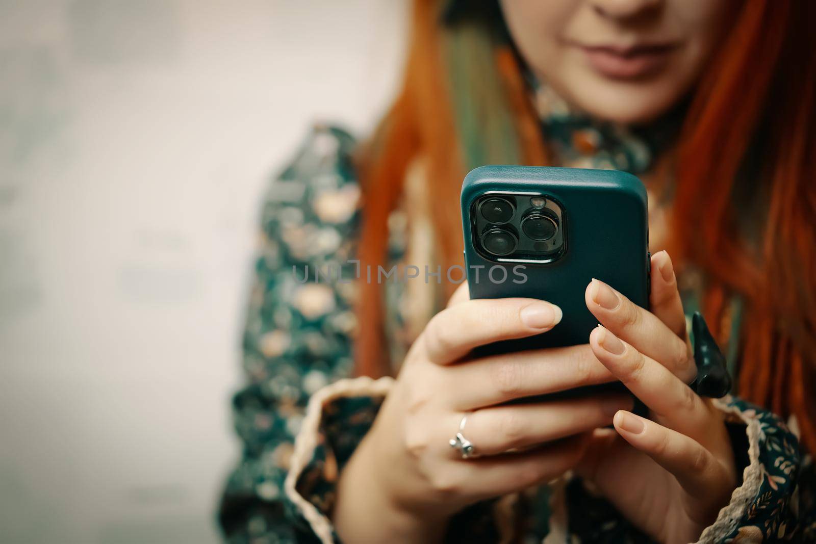 Blogger holds iPhone 13 pro and looks at smartphone screen. Mobile phone in women's hands. Photos for advertising apps and gadgets with copy space. Bishkek, Kyrgyzstan - January 24, 2022