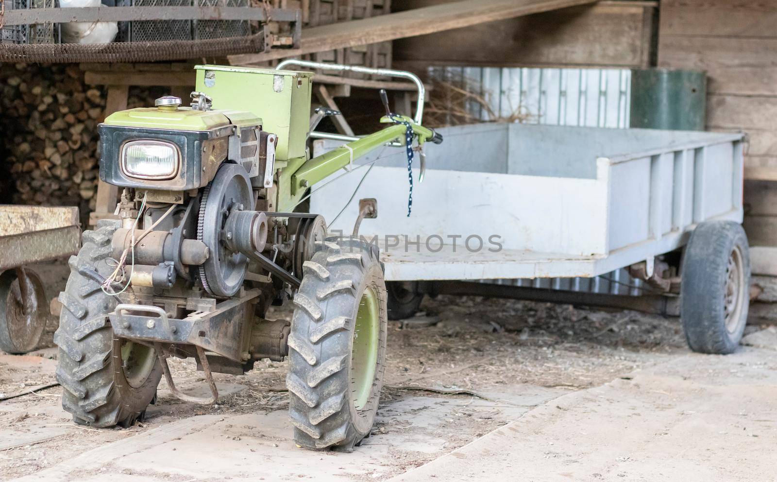 Typical heavy diesel walking tractor with trailer. Agricultural transport equipment of the countryside. Portable agricultural equipment, walking minitractor. The start system is mechanical and manual