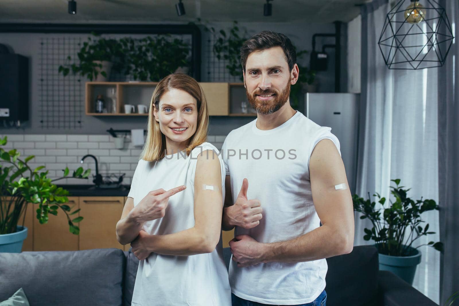 Married couple man and woman, vaccinated look at the camera and smile, show on the shoulders of the injection site